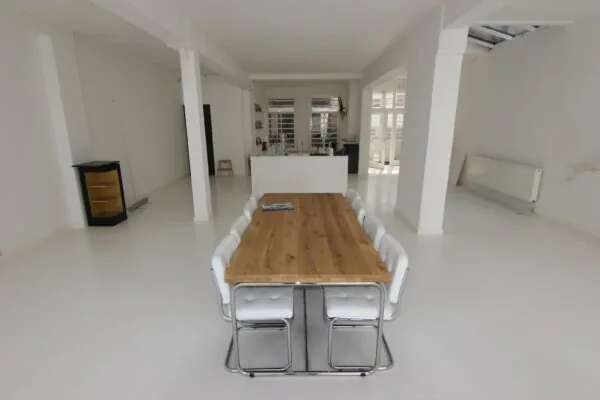 Lichte, minimalistische eetkamer aan de Graaf Florisstraat met een lange houten tafel en witte stoelen.